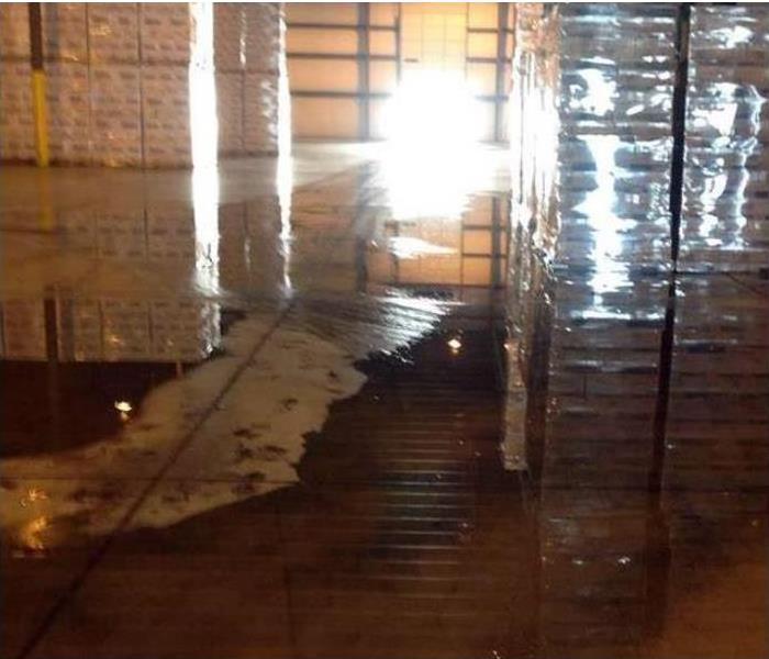 water covering floor of warehouse, stacked inventory nearby